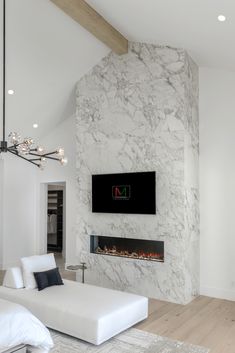 a large white living room with a fireplace and tv mounted on the wall above it