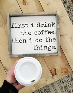 a person holding a coffee cup in front of a sign that says, first i drink the coffee then i do the things