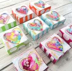 several colorful boxes with hearts on them sitting on a wooden table next to each other