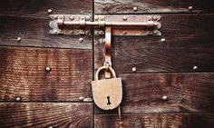 an old padlock on the side of a wooden door that has a key in it