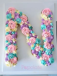 the letter m made out of cupcakes is decorated with pink, blue and purple flowers