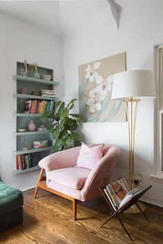 a living room with a pink chair and bookshelf