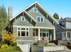 a gray house with white trim on the front and side windows is shown in this image