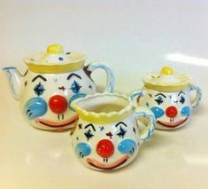 three ceramic jugs with clown faces painted on the sides and one has a yellow top