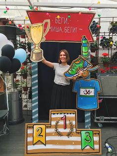 a woman standing in front of a booth with trophies and medals on it's sides