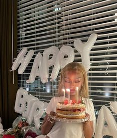 a woman holding a cake with candles in front of her face and the words happy birthday on it