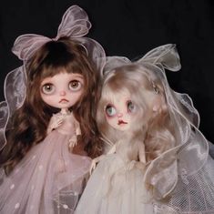 two dolls dressed in white are posed together