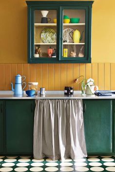 a kitchen with yellow walls and green cabinetry, black and white checkered floor