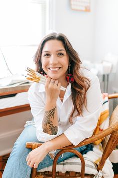 a woman sitting in a chair with her hand on her chin and smiling at the camera