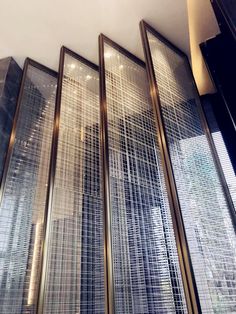 four tall glass doors in front of a wall with metal mesh coverings on them