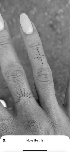 a woman's hand with a cross tattoo on her left thumb and the word more like this written in cursive ink