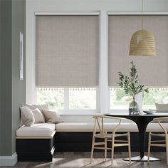 a dining room table with chairs and a bench in front of two windows that have roman shades on them