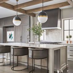 a large kitchen with two bar stools next to an island in the middle of it