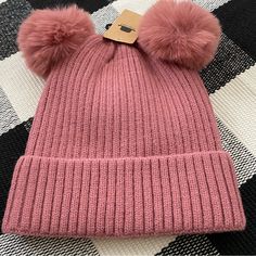 a pink hat with two pompoms on it