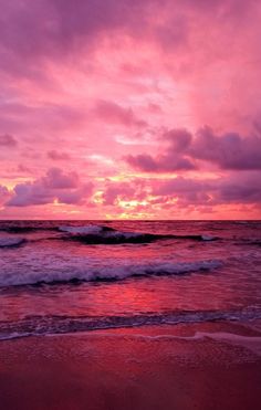 the sun is setting over the ocean with waves coming in to shore and pink clouds