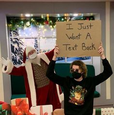 two people dressed as santa clause and one is holding up a sign that says i just want a text back