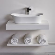 a white sink sitting on top of a counter next to towels and a faucet