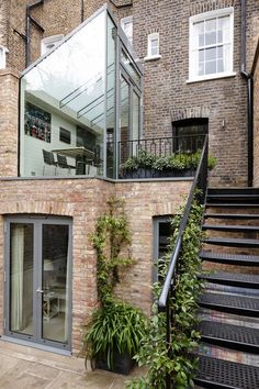 a brick building with stairs leading up to the second floor and an outdoor dining area