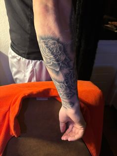 a man with a rose tattoo on his arm is holding onto an orange cloth bag