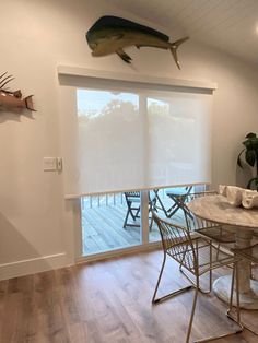 a fish mounted on the wall above a table and chairs in a room with wood floors