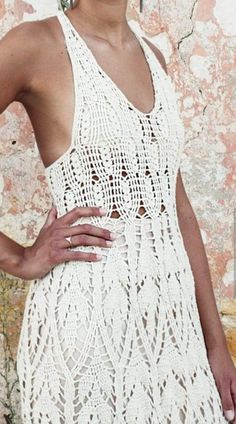 a woman in a white crochet dress posing for a photo with her hands on her hips