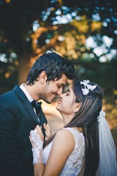 a bride and groom standing close together in the woods