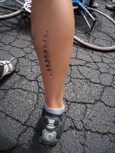 a person with a tattoo on their leg standing next to some parked bikes and bicycles