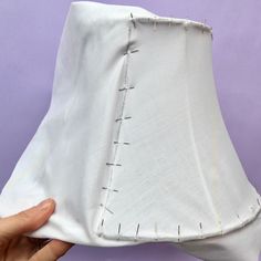 someone is stitching the fabric on top of a lamp shade with pins and needles