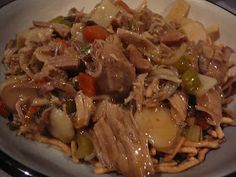 a white plate topped with meat and veggies covered in gravy on top of a table