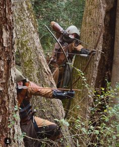 two men in the woods with their backs turned to look like they are aiming at something