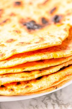 a stack of tortillas sitting on top of a white plate