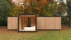 an open room in the middle of a field with leaves on the ground and trees around it