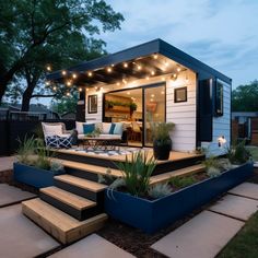 a small house with steps leading up to the front door and patio area, lit by string lights