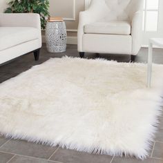 a living room with two white chairs and a rug