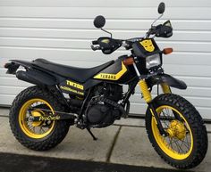 a yellow and black dirt bike parked in front of a garage door on the sidewalk