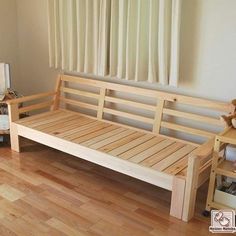 a wooden bed frame sitting on top of a hard wood floor next to a window