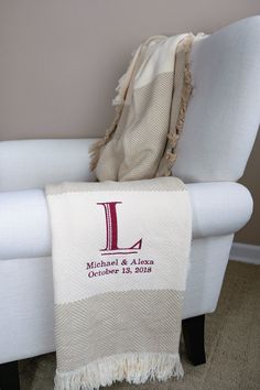 a white chair with a blanket on top of it and a monogrammed l