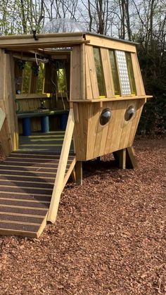 a wooden play structure with stairs leading up to the door and steps down to it