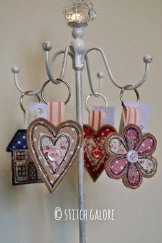 two hearts hanging from a metal stand with tags attached to it's sides and the words stitch galore on them