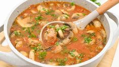 a large pot filled with soup on top of a wooden cutting board