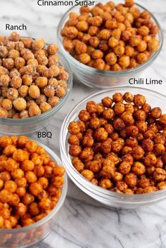 four glass bowls filled with different kinds of chickpeas on top of a marble counter