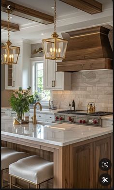 a kitchen with white cabinets and marble counter tops, gold pendant lights hanging from the ceiling