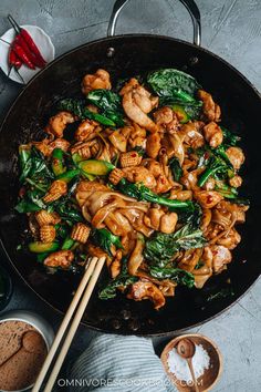 chicken and spinach stir fry in a wok with chopsticks on the side