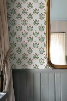 a mirror sitting on top of a wooden table next to a wallpapered wall