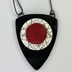 a black and white necklace with a red circle on it