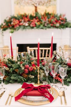 a table set for christmas dinner with candles and decorations