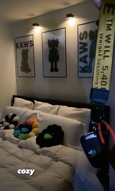 a bed with pillows and stuffed animals on it in a room that has three framed pictures