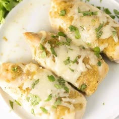 three pieces of chicken covered in cheese and parsley on a white plate with lettuce