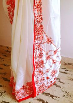 "Stunning half white semi silk saree with intricate all over embroidery and semi raw silk unstiched blouse in reddish orange. The red color thread embroidery is simply stunning aginst offwhite. The entire embroidery is hand worked and the floral border extends more in the front, pallu and the pleats. Saree length 5.5 meters Blouse fabric 1 meter 44\" wide Saree ships in 2-3 days of payment. Delivery within 4-5 days of shipment all over the world. We also offer blouse and petticoat stitching for White Bollywood Blouse Piece With Floral Embroidery, Red Embroidered Border Chanderi Saree, Semi-stitched Red Saree With Embroidered Border, Red Unstitched Saree With Embroidered Border, Red Art Silk Saree With Floral Embroidery, Red Chanderi Blouse Piece With Floral Embroidery, White Semi-stitched Blouse With Floral Embroidery, Red Semi-stitched Saree With Embroidered Border, Red Chanderi Saree With Embroidered Border