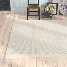 a white rug in the middle of a room with two chairs and flowers on the floor